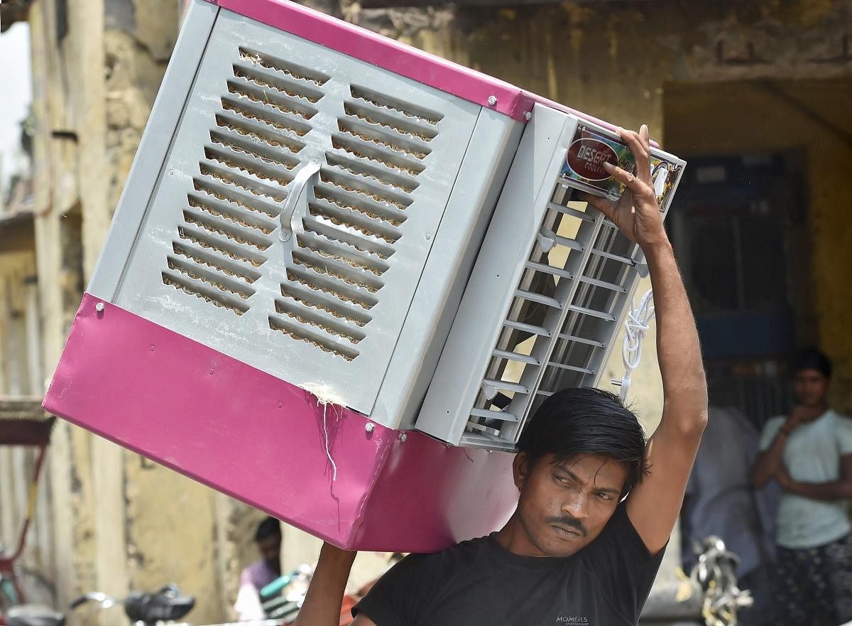 A worker carries an air cooler as temperature soars on a hot, summer day, in New Delhi. PTI Photo