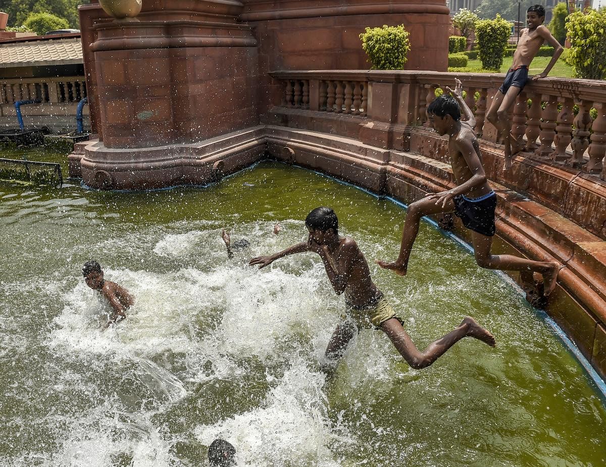 Children play at a water body near Vijay Chowk, during a hot day in New Delhi. PTI Photo
