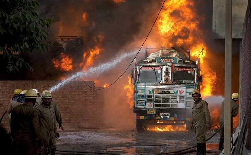 Firefighters douse flames on a truck which caught fire at Malviya Nagar in New Delhi, on Tuesday, May 29, 2018. The truck fire later spread to a nearby godown. (PTI Photo)