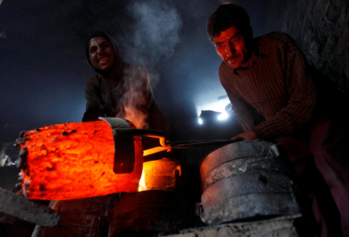 Workers pour melted copper in a mould to make utensils and accessories inside a workshop in Srinagar March 27, 2014. REUTERS/Danish Ismail