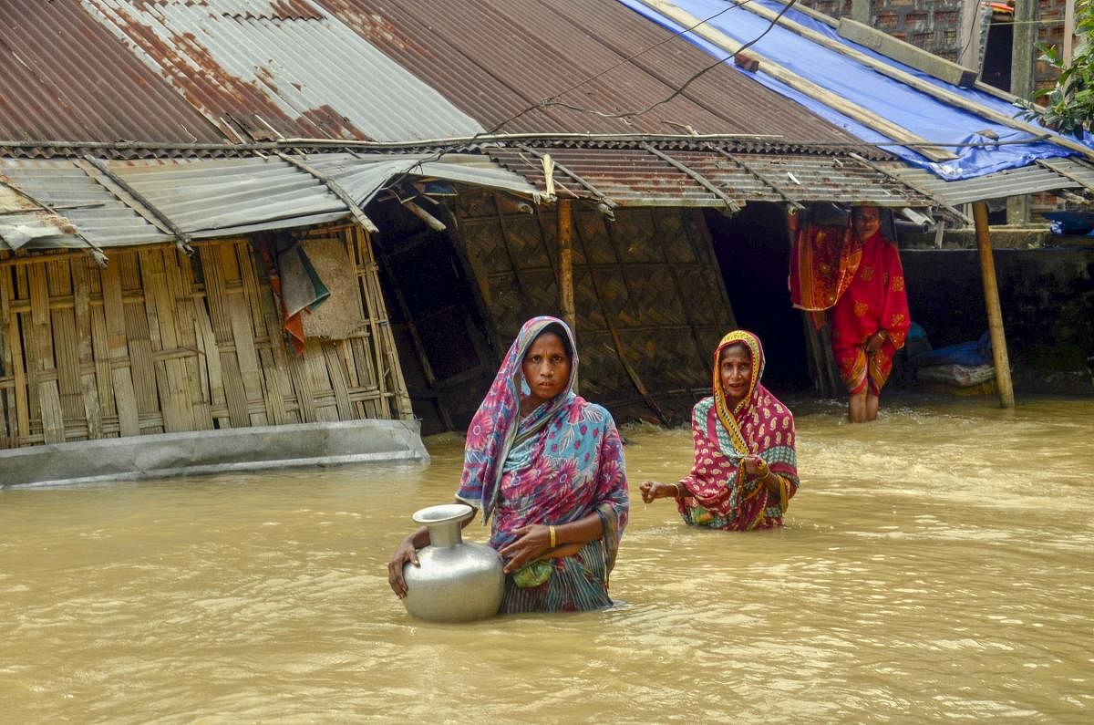 Villagers carry clean water as they wade across flood-affected areas at Nilambazar village, in Karimganj. PTI Photo