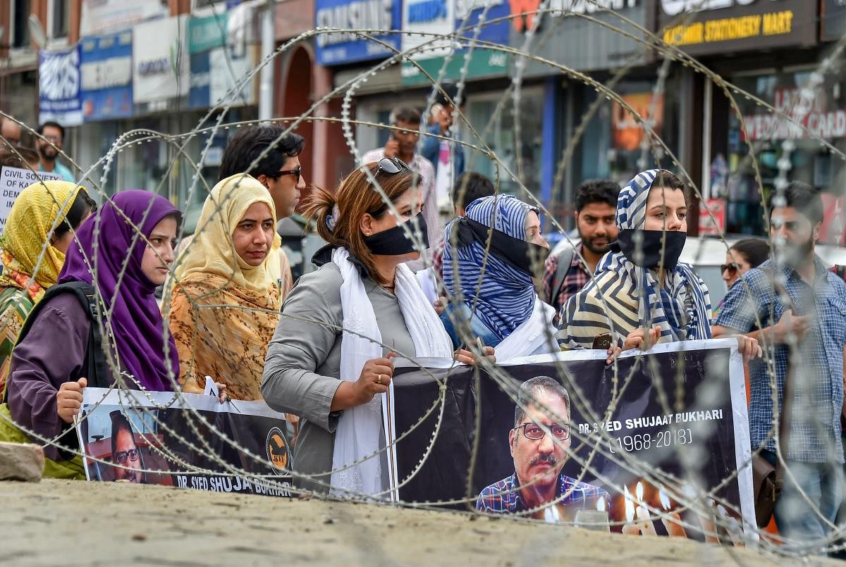 Journalists hold placards during a silent protest march against the killing of Rising Kashmir newspaper editor-in-chief Shujaat Bukhari, in Srinagar on Tuesday, June 26, 2018. PTI