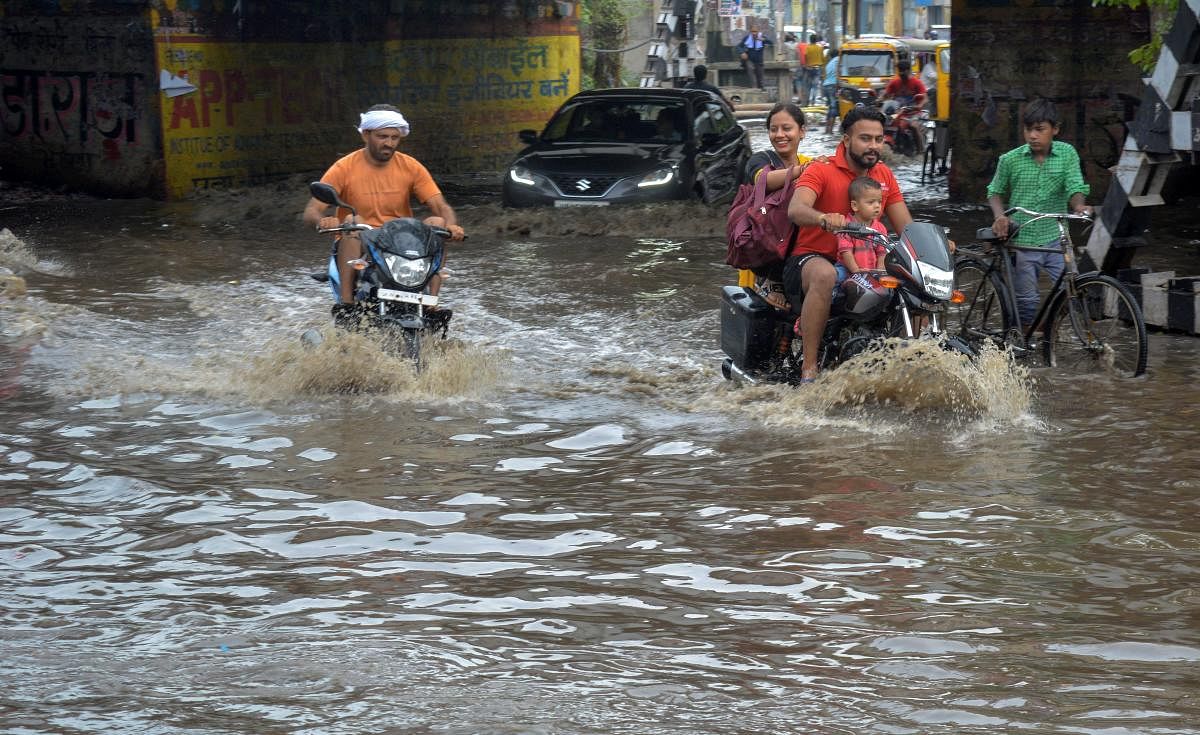 Commuters ride through a waterlogged street during heavy rainfall, in Mathura on Thursday, June 28, 2018. PTI