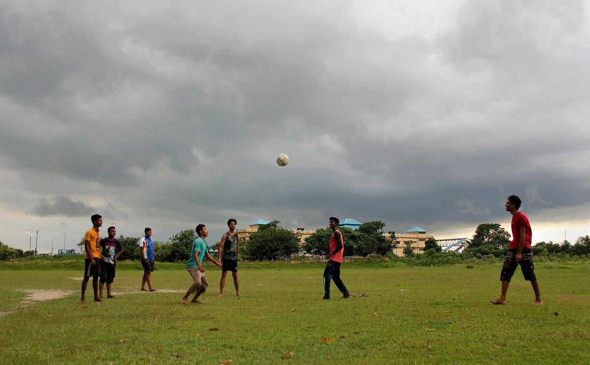 Youth play football as monsoon clouds hover in the sky at Balurghat in South Dinajpur district of West Bengal on Friday, June 29, 2018. (PTI Photo)