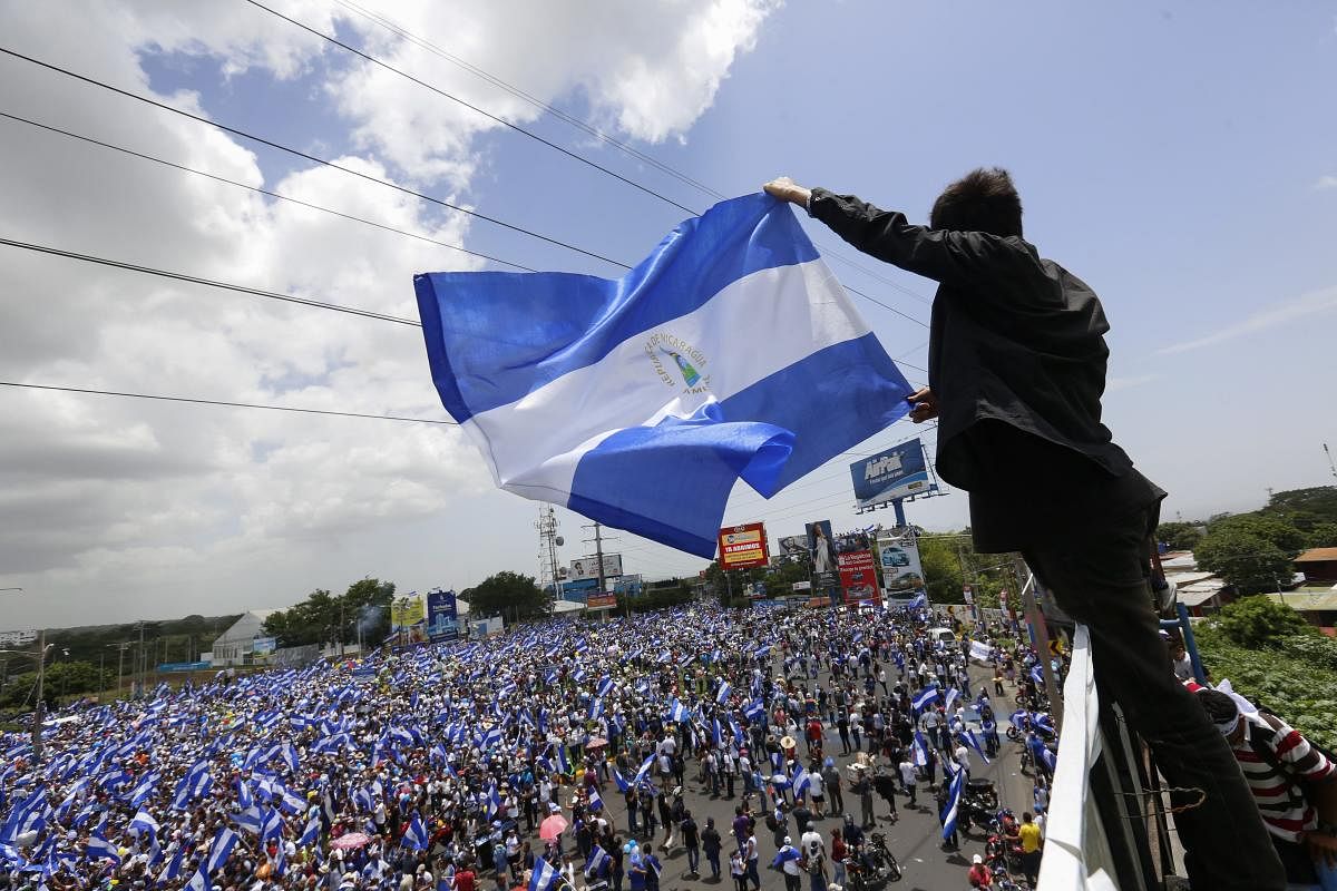 A man waves a Nicaraguan flag as people participate in a demonstration called the