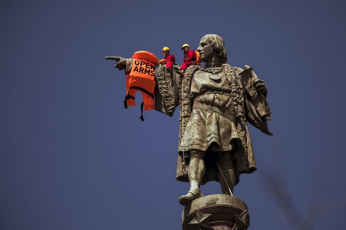 Two activists sits on top of the 60-meter (197-feet) monument Christopher Columbus tower after placing a vest with the words