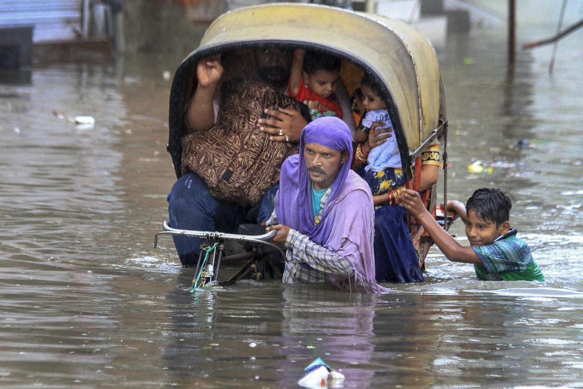 A rickshaw puller ferries his passengers through water-logged streets during heavy rainfall, in Bathinda on Wednesday, July 04, 2018. (PTI Photo)