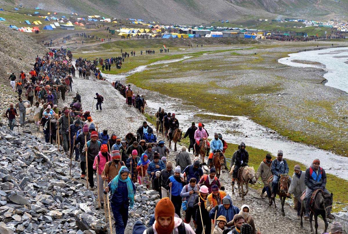 Pilgrims cross mountain trails during their religious journey to the Amarnath cave temple, at Pahalgam in Anantnag district of J&K on Friday, July 06, 2018. The Amarnath pilgrimage remained suspended for the second day today as inclement weather in the Valley had left thousands of pilgrims stranded at both Baltal and Pahalgam base camps from where the pilgrims proceed by foot to pay obeisance at 3880-metre high cave shrine. (PTI Photo)