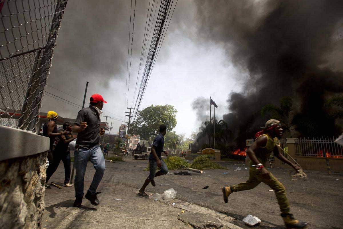 People run away to protect themselves from police officers while cars burn in the garage of the Royal Oasis hotel during a protest over the cost of fuel in Port-au-Prince, Haiti, Saturday, July 7, 2018. The Haitian government suspended a fuel price hike Saturday hours after demonstrators attacked a Best Western Premiere hotel in one of the wealthiest neighborhoods of the capital.AP/PTI