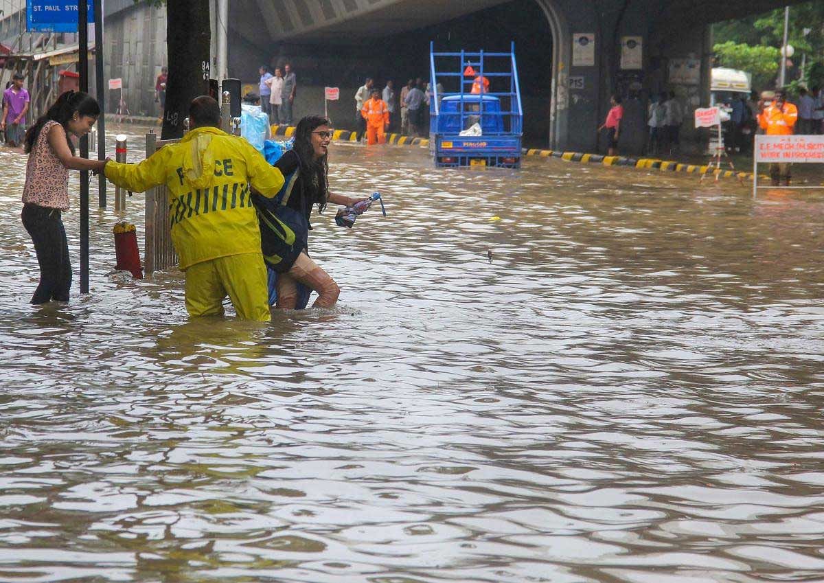 People wade through water-logged streets after heavy rainfall, in Mumbai on Sunday, July 08, 2018. (PTI Photo)