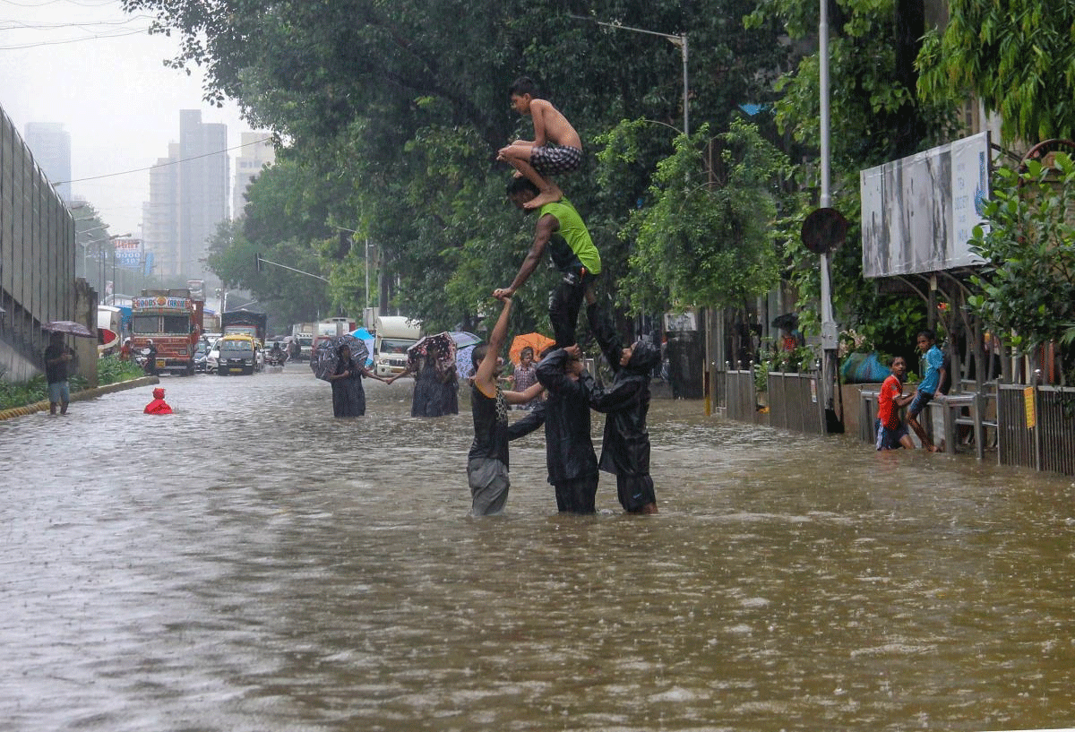People create a human pyramid on a water-logged street after heavy rainfall at Dadar, in Mumbai on Monday, July 9, 2018. (PTI Photo)