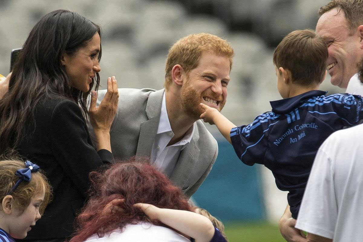 A boy strokes Prince Harry's beard, as Meghan, the Duchess of Sussex, smiles on the pitch at Croke Park on the second day of their visit to Dublin, Ireland, Wednesday July 11, 2018. AP/PTI