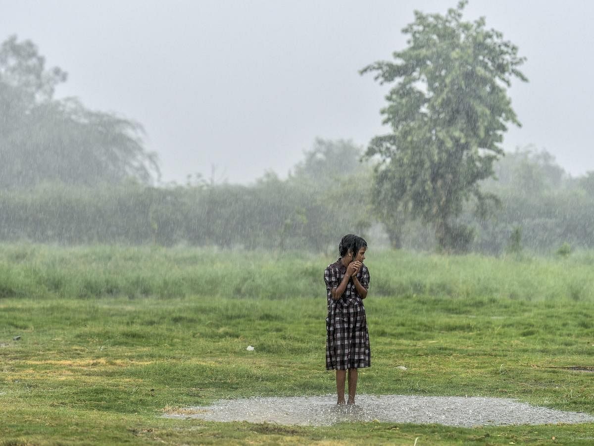 A child gets soaked in an open field, during heavy rainfall, at Yamuna village in New Delhi on Friday, July 13, 2018. (PTI Photo/Arun Sharma)