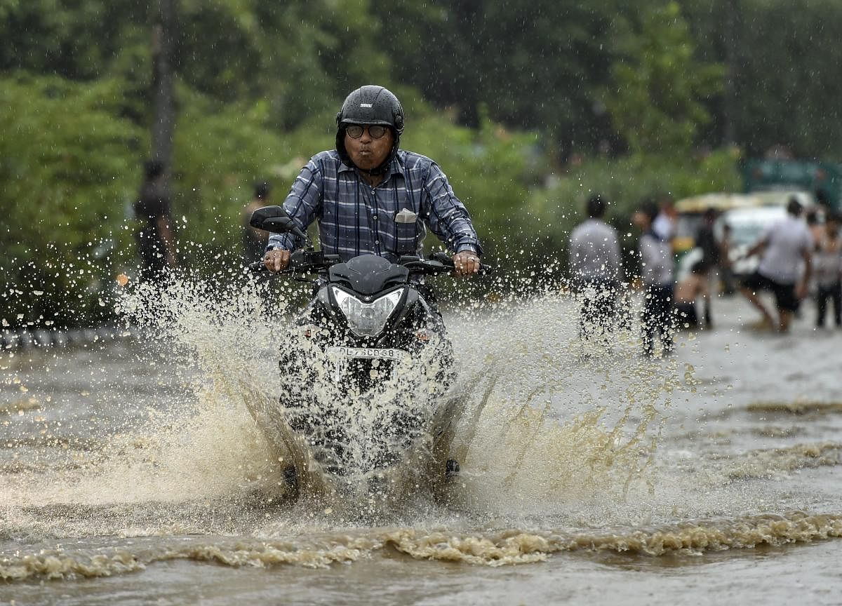 A commuter rides on a scooter during heavy rainfall, in New Delhi on Friday, July 13, 2018. (PTI Photo/Arun Sharma)