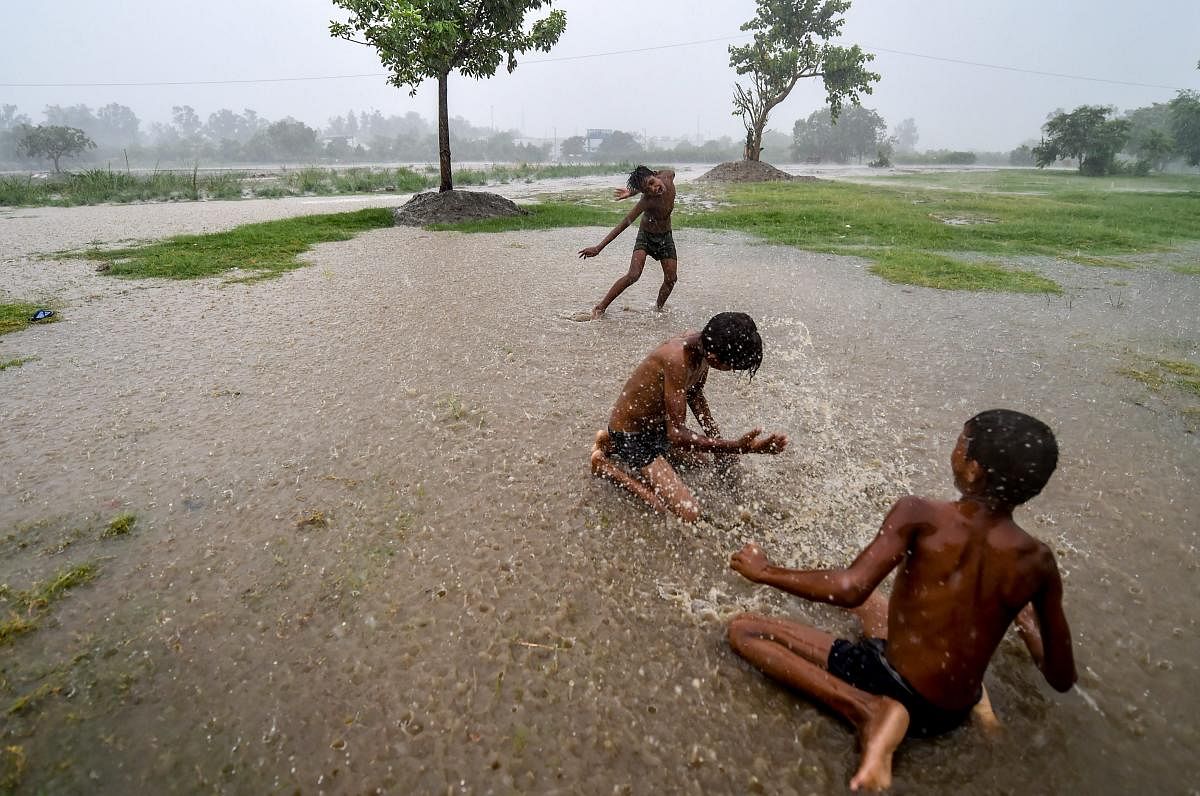 Children play In an open field, during heavy rainfall, at Yamuna village in New Delhi on Friday, July 13, 2018. (PTI Photo/Arun Sharma)