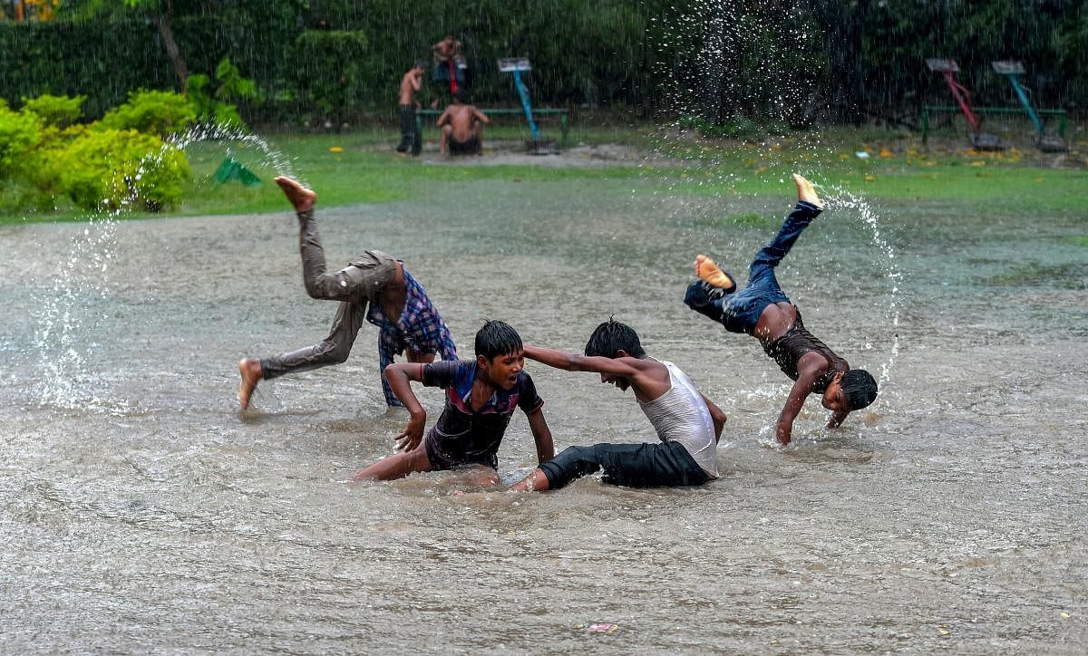 Children play on an open field during heavy rainfall, at Shalimar Bagh in New Delhi on Friday, July 13, 2018. (PTI Photo/Shahbaz Khan)