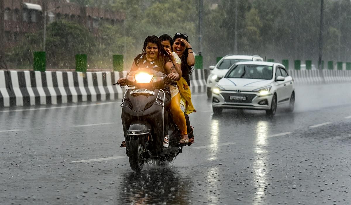 Commuters ride on a scooter during heavy rainfall, in New Delhi on Friday, July 13, 2018. (PTI Photo/Atul Yadav)