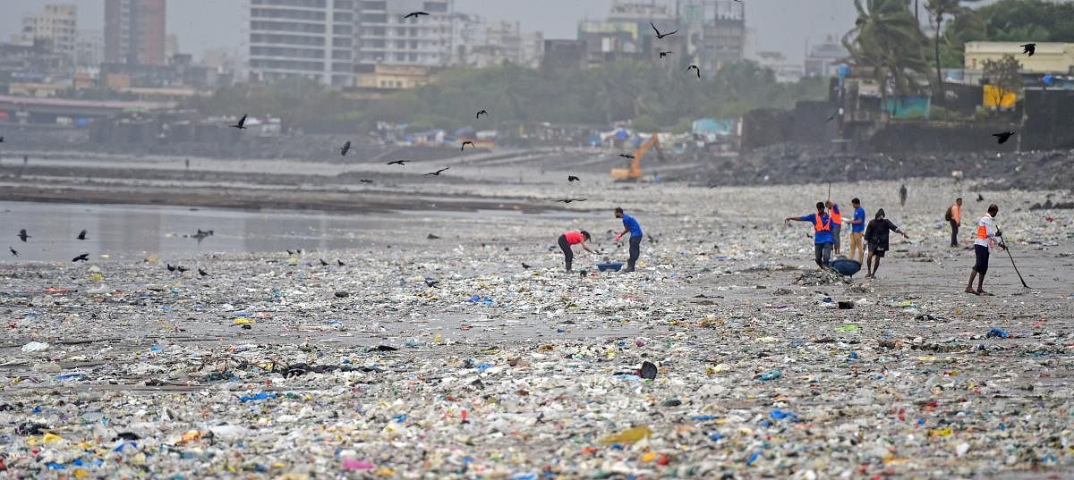 Brihanmumbai Municipal Corporation (BMC) workers clear the garbage washed ashore after a high tide on Mahim beach, in Mumbai on Saturday, July 14, 2018. (PTI Photo/Shashank Parade)
