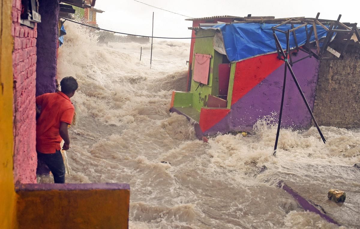 A man watches a high tide seawave as it enters the shanty town near the shore, at Bandra in Mumbai on Saturday, July 14, 2018. (PTI Photo/Shashank Parade)