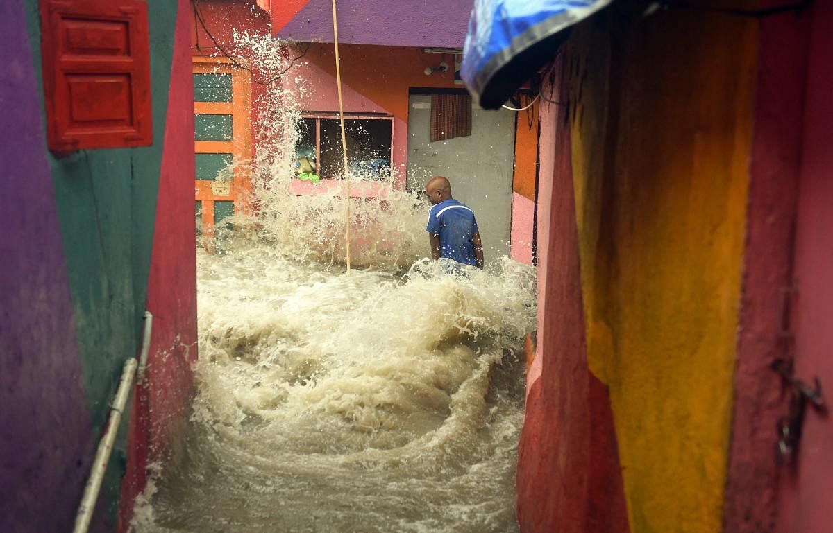 A high tide wave hits a man standing outside his house as the seawater enters the shanty town near the shore, at Bandra in Mumbai on Saturday, July 14, 2018. The man was washed away by the wave and rescued by rescuers a few meters away from the spot. (PTI Photo/Shashank Parade)