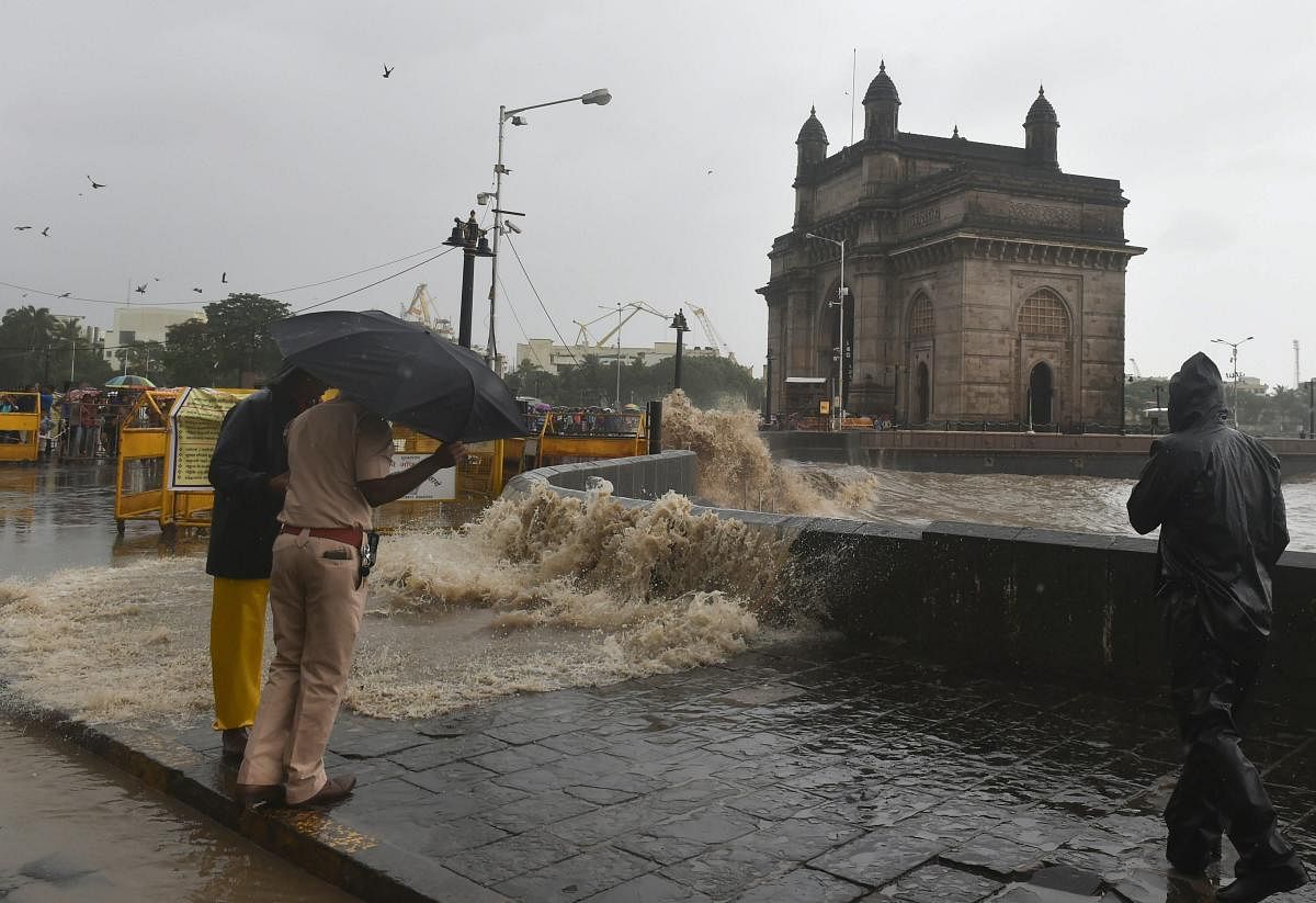 Policemen stand near the shore as a high tide wave hits the sea wall at Gateway of India, in Mumbai on Sunday, July 15, 2018. (PTI Photo/ Mitesh Bhuvad)
