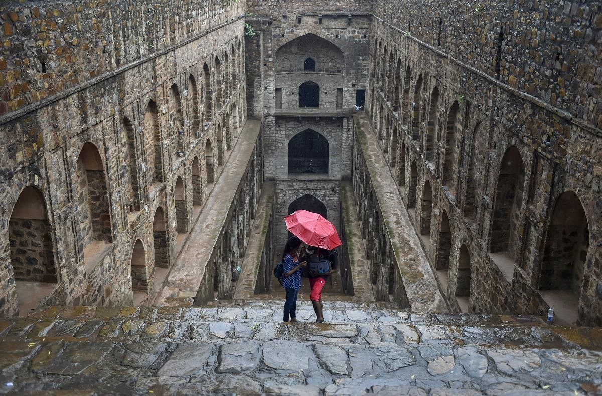People protect themselves under an umbrella during heavy rainfall at Agrasen ki Baoli, in New Delhi, on Monday, July 16, 2018. (PTI Photo/Ravi Choudhary)