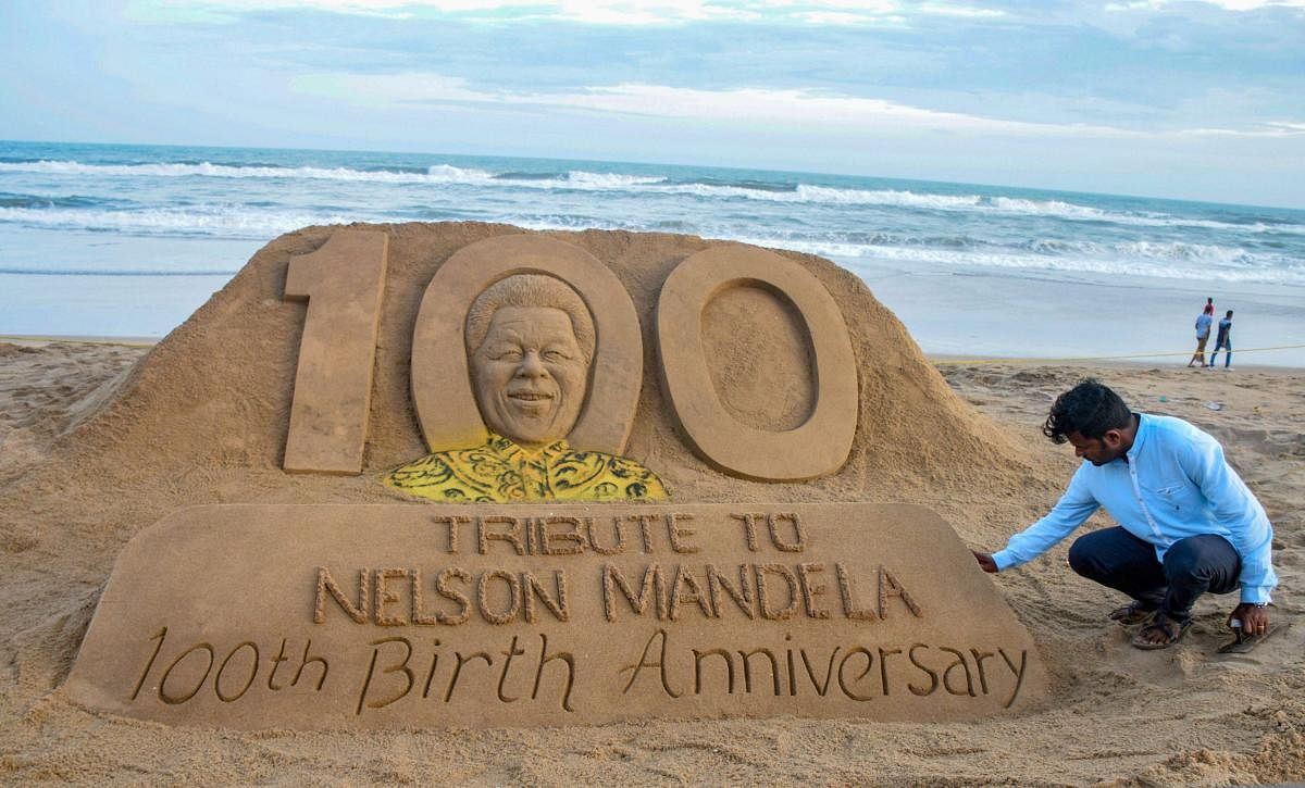 Sand artist Sudarsan Pattnaik creates a sand sculptor of Nelson Mandela on the eve of his 100th birth anniversary, in Puri on Tuesday. (PTI Photo)