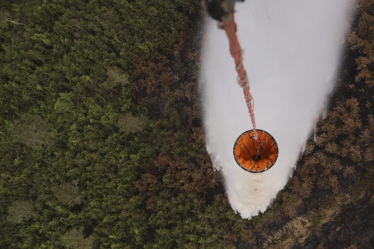 A helicopter drops water to extinguish a forest fire in Pali, South Sumatra, Indonesia. (AP/PTI Photo)