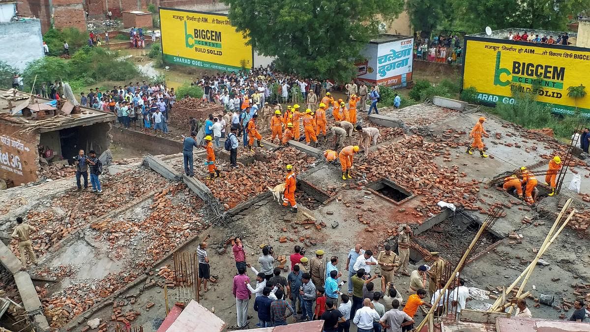 Members of the National Disaster Response Force (NDRF) conduct a rescue operation after a four-storey building collapsed in Ghaziabad, Uttar Pradesh. (PTI Photo)