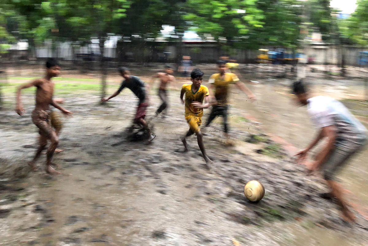Boys play football on muddy ground of a park during rain in Dhaka, Bangladesh. (Reuters Photo)