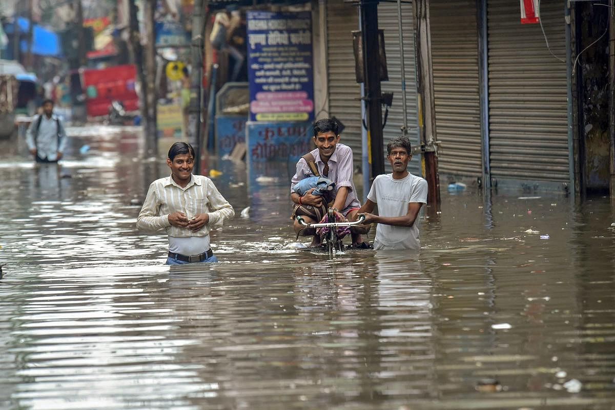 Patna: People wade through a waterlogged street after monsoon rainfall, in Patna on Saturday, July 28, 2018. (PTI Photo)
