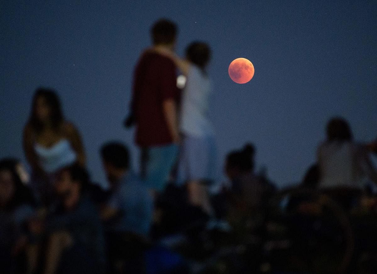 Munich: dpatop - People observe the lunar eclipse on the Olympic mountain in Munich, Germany, 27 July 2018. The world witnessd the longest total lunar eclipse in the century that left the moon in a spectacular red colour for 1 hour and 43 minutes while the partial phase continued for more than 6 hours. Photo: DPA/PTI