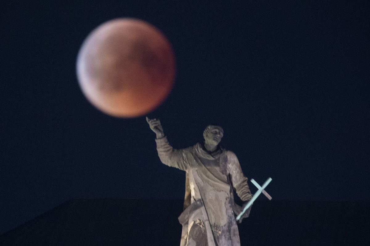 Dresden: The full moon is seen over the Mattielli statue at the Dresden Cathedral during a lunar eclipse in Dresden, Germany, 27 July 2018. The world witnessd the longest total lunar eclipse in the century that left the moon in a spectacular red colour for 1 hour and 43 minutes while the partial phase continued for more than 6 hours. Photo: DPA/PTI