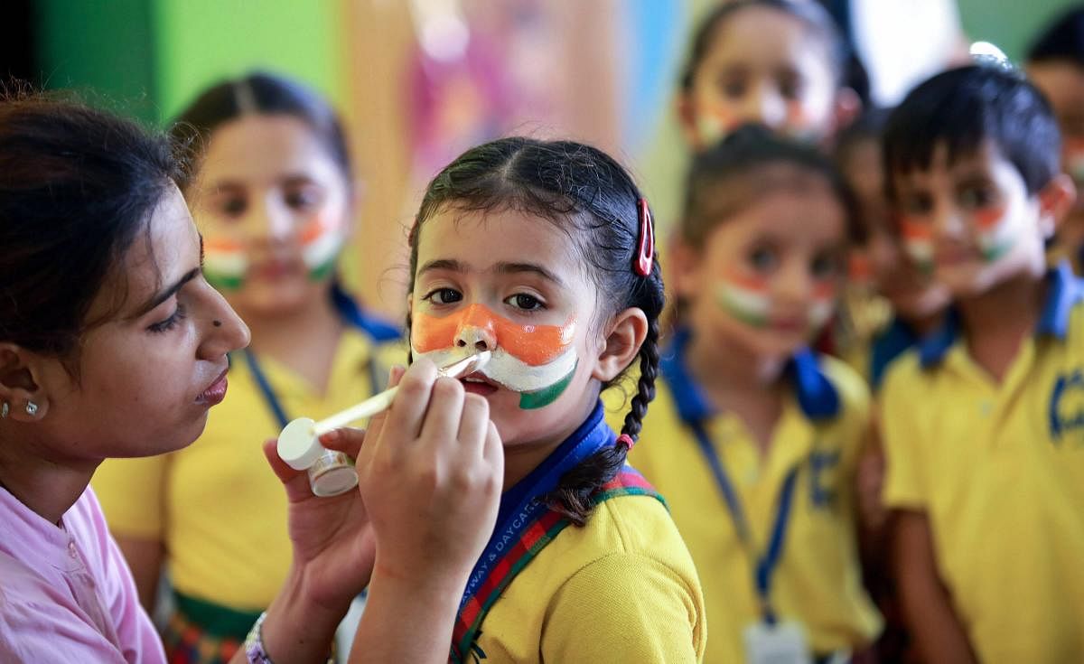 School children with their faces painted with Indian flag colors take part in a programme in an Independence Day function at a school in Jammu on Saturday. (PTI Photo)