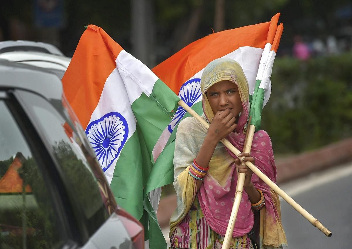A woman street vendor sells Indian tri-colours at an inter-section in New Delhi on Sunday, Aug12, 2018. Flags are in demand ahead of Independence day celebrations. (PTI Photo)