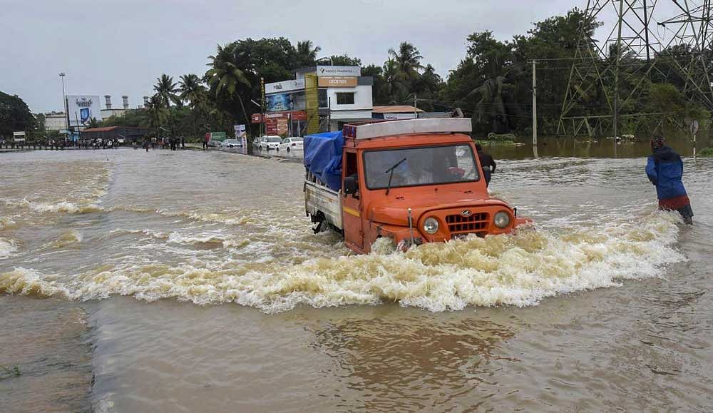 Commuters wade across waterlogged streets as heavy monsoon rains causes floods, in Kochi. PTI Photo