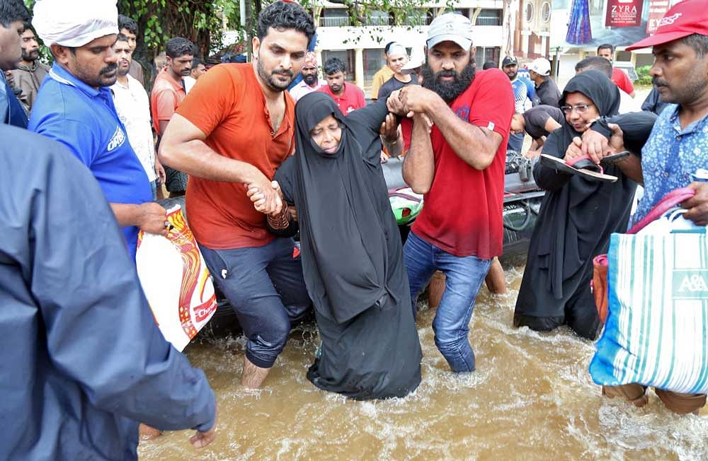 Rescuers help a woman to move through a water-logged road after she was evacuated from a flooded area in Aluva in the southern state of Kerala. Reuters Photo