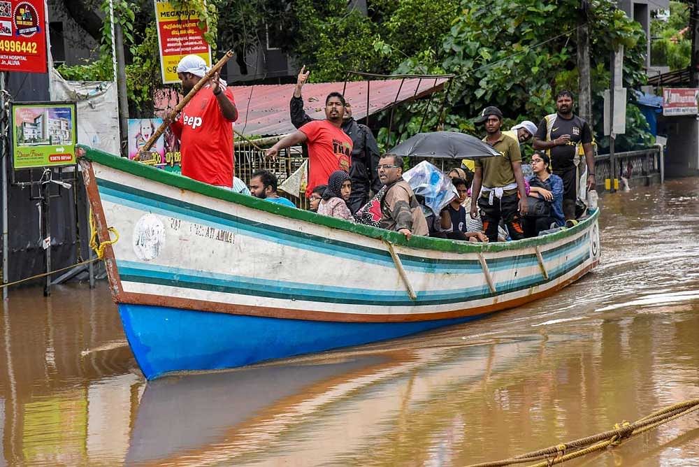 Rescue workers row a boat carrying locals who were stranded in floods following heavy monsoon rainfall, in Kochi. PTI Photo