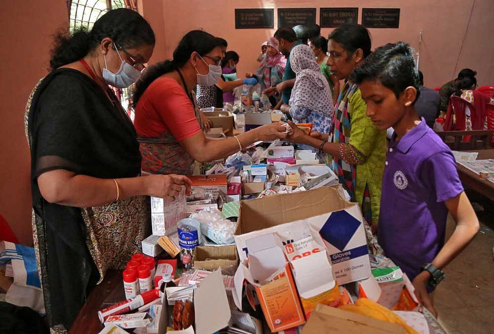 Flood-affected people receive free medicines inside a college, which has been converted into a temporary relief camp, in Aluva, Kerala. Reuters