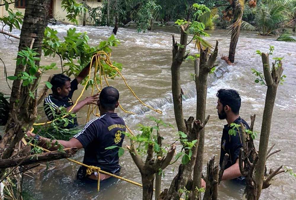 Navy personnel along with volunteers rescue people who were trapped in the flood-hit areas in Thrissur district on Monday. PTI Photo