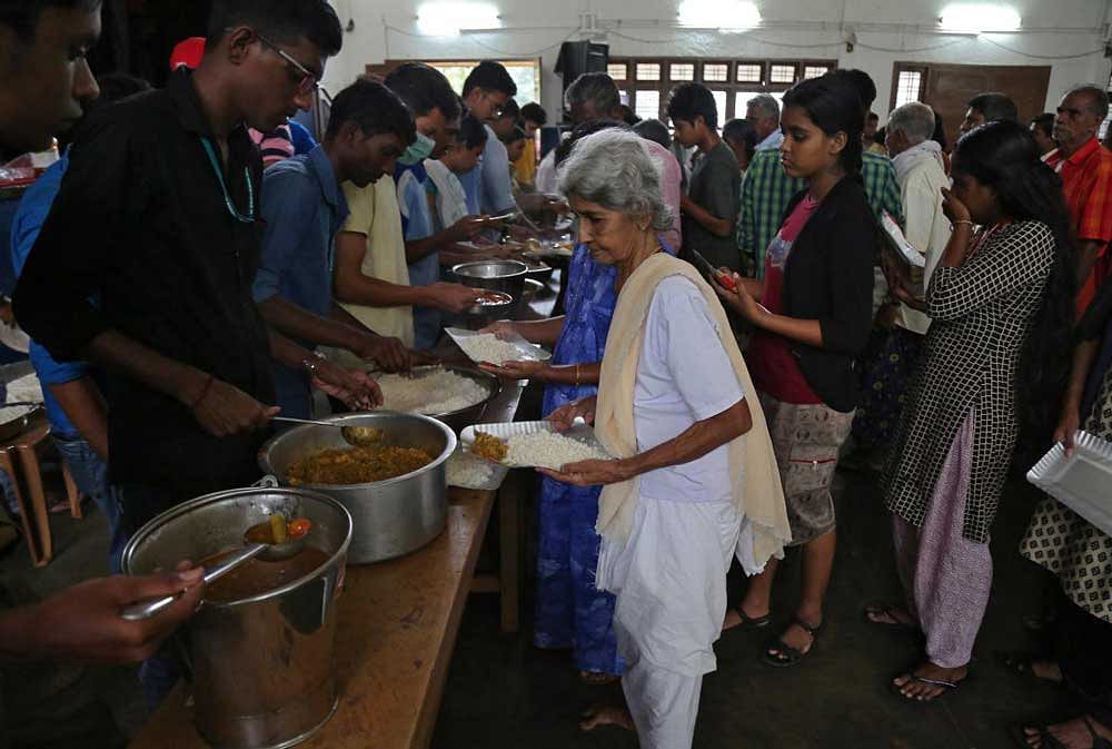 A flood-affected woman receives food inside a college auditorium, which has been converted into a temporary relief camp, in Kochi, Kerala. REUTERS Photo