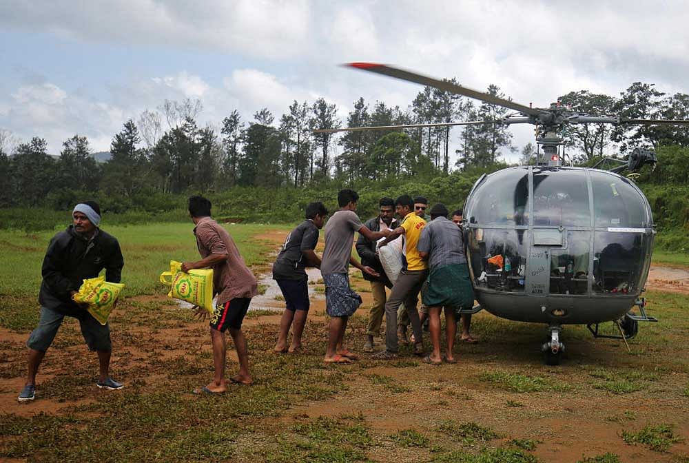 Flood victims unload food and relief material from an Indian Air force helicopter at Nelliyampathy Village, Kerala. Reuters