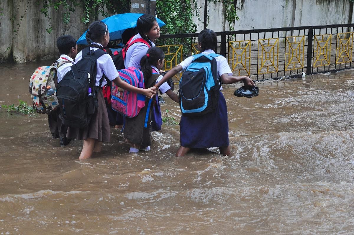 Schoolchildren wade across waterlogged street following monsoon rainfall, in Guwahati on Friday, Aug 24, 2018. PTI
