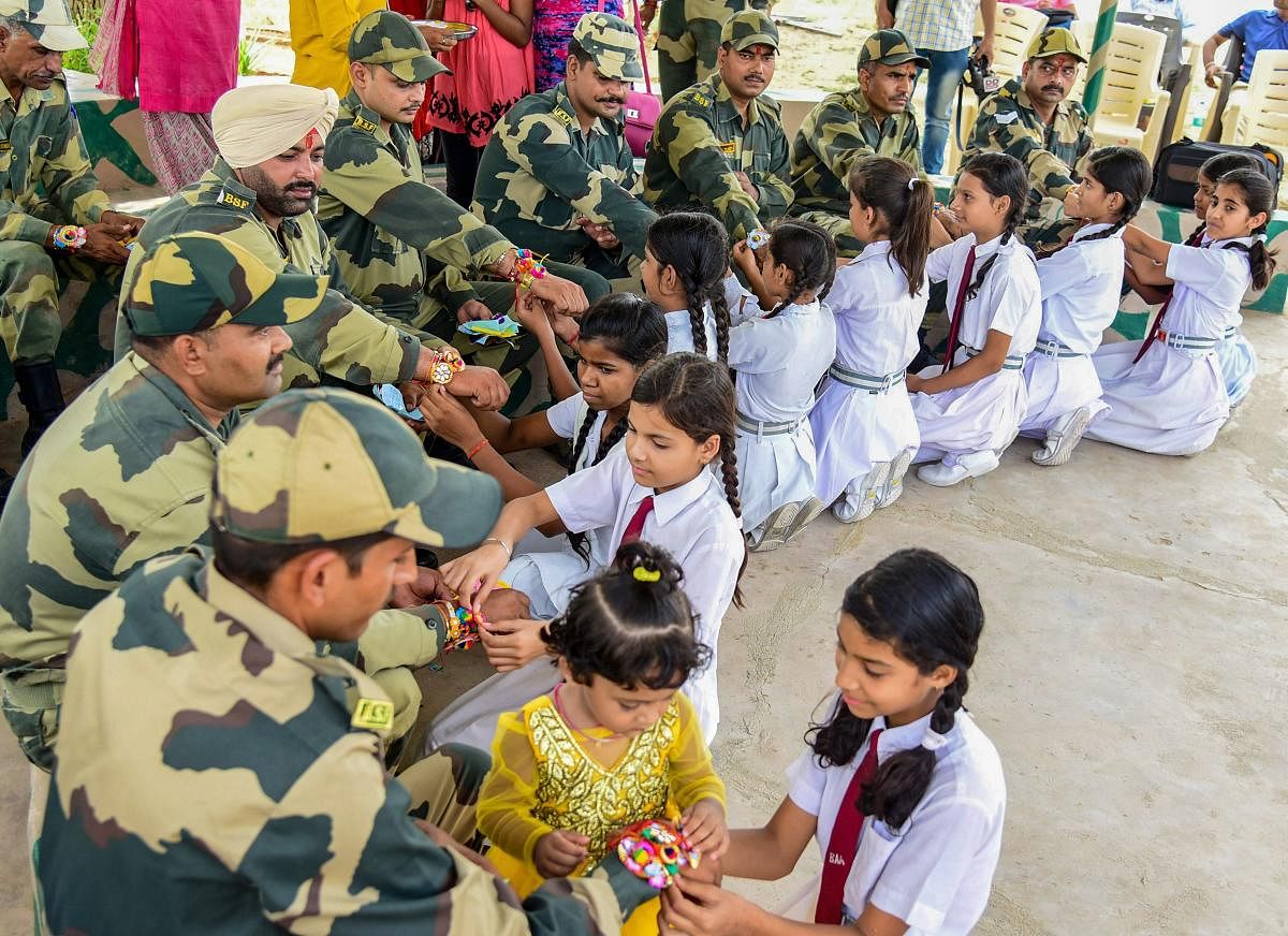 Students tie rakhis on the wrists of BSF personnel on the eve of Raksha Bandhan, in Bikaner on Saturday, Aug 25, 2018. PTI