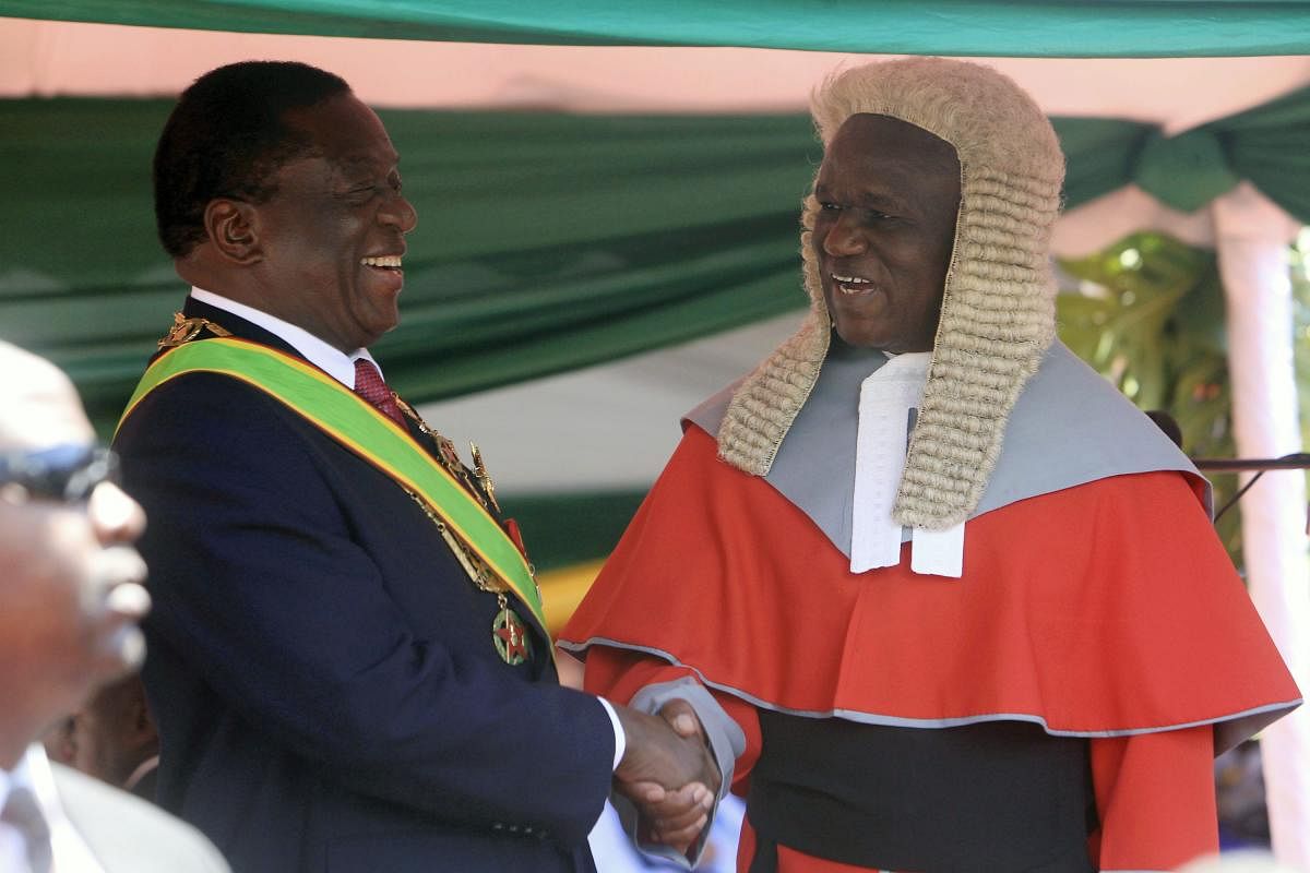 Zimbabwean President Emmerson Mnangagwa,left, is congratulated by Chief Justice Luke Malaba after taking his oath during his inauguration ceremony at the National Sports Stadium in Harare, Sunday, Aug. 26, 2018. The Constitutional Court upheld Mnangagwa's narrow election win Friday, saying the opposition did not provide