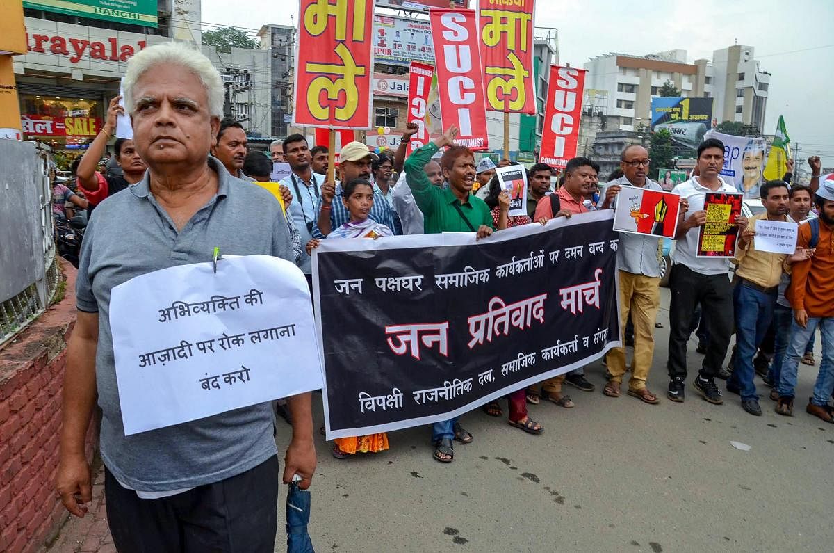 Social activists and filmmakers hold placards during a protest against the raid at activist Stan Swamy's residence, in Ranchi on Thursday, Aug 30, 2018. PTI