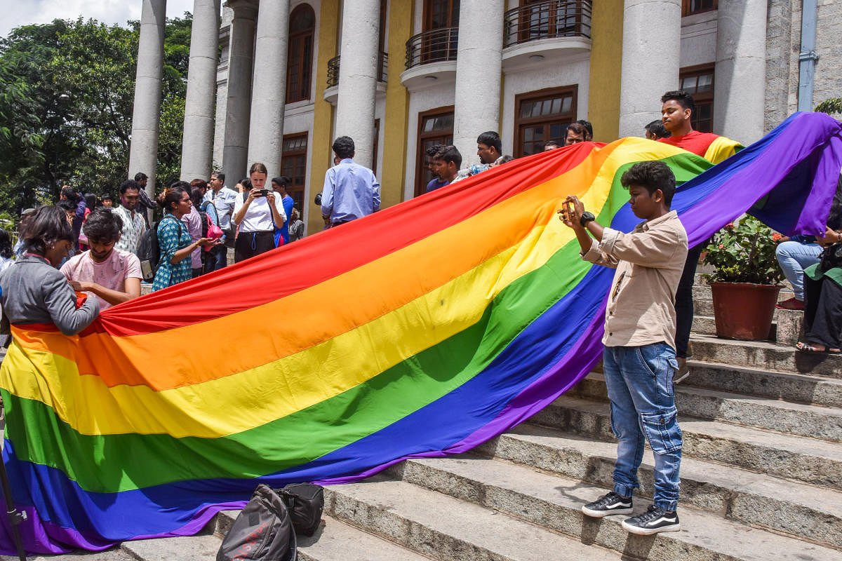 LGBTQ community people, with a rainbow flag, celebrate the Supreme Court verdict which decriminalises consensual gay sex, in front of Town Hall in Bengaluru. (DH Photo)
