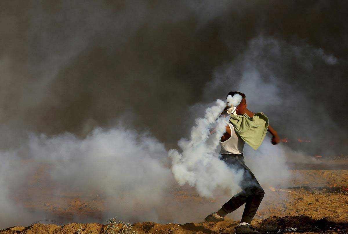A protesters throws back a teargas canister fired by Israeli troops while other burn tires near the fence of Gaza Strip border with Israel, during a protest, east of Gaza City, Friday, Sept. 7, 2018. A teenager was killed and dozens of other Palestinians injured by Israeli fire at a border protest, Gaza officials said. AP/PTI