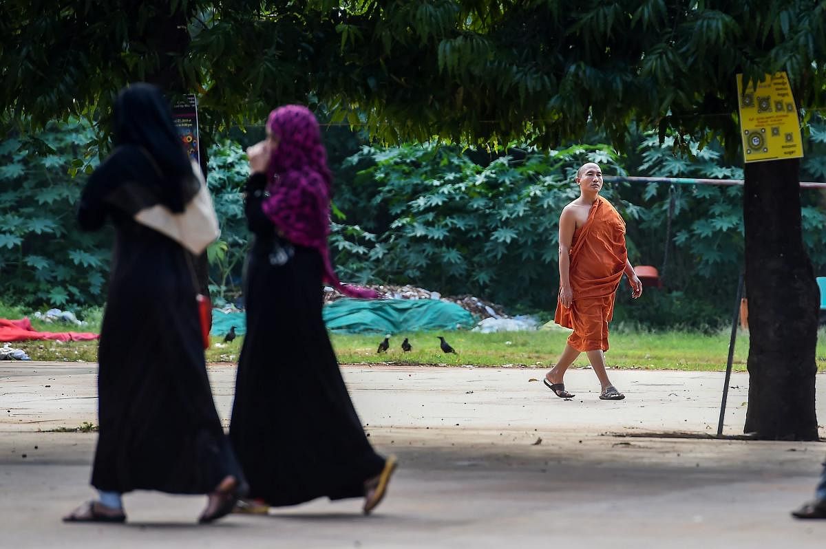 Bengaluru: A Buddhist monk walks past activists during the 'Baatein Aman Ki' campaign that aims to sensitise people about violence against women, in Bengaluru, Thursday, Sept 27, 2018. (PTI Photo/Shailendra Bhojak)