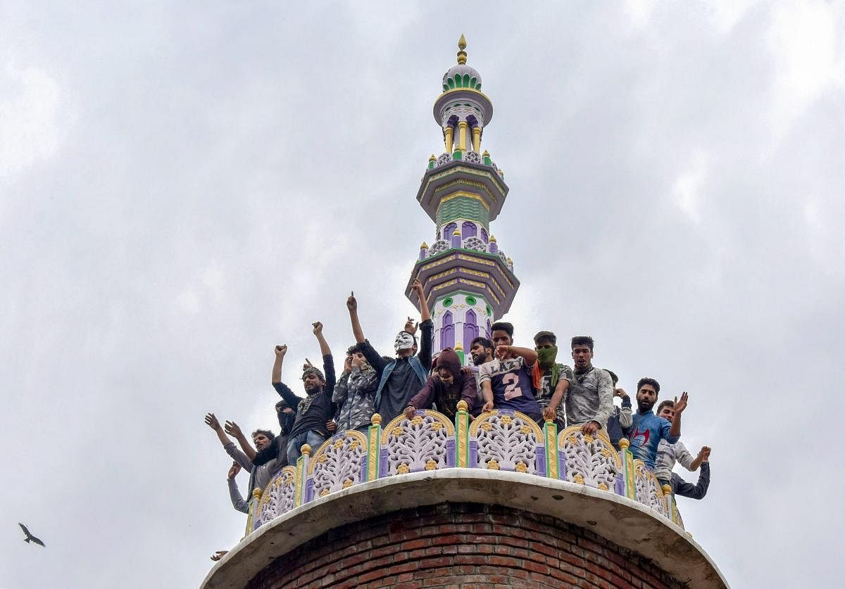 Budgam: People raise slogans from the tomb of a mosque, where militants were hiding during an encounter with security forces, at Panzan Chadoora area of Budgam district near Srinagar, Thursday, Sept 27, 2018. Five persons, including three militants, were killed in three separate incidents. (PTI Photo)